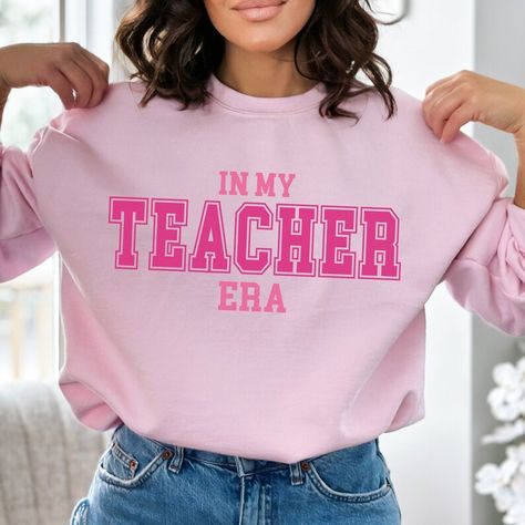 Introducing our fabulous Gildan 18000 sweatshirt, designed to make a statement! Embrace the nostalgic charm of yesteryears with our In My Teacher Era sweatshirt. Crafted with premium quality materials, this cozy sweatshirt guarantees ultimate comfort. The eye-catching detail is its big, bold, and vibrant pink college font print, adding a stylish pop to your wardrobe.