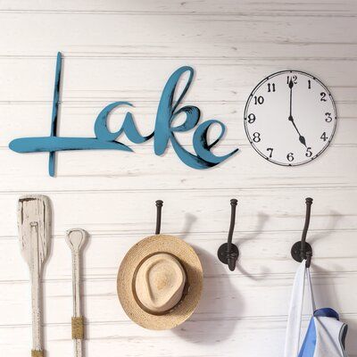 Dress up your lake house's look or just bring a bit of rustic flair into a dwelling more land-locked with this two-piece wall decor set. Made in the USA, this pleasant pair is artistically hand-painted on light-weight resistant PVC with cool hues of blue, black, and white. One piece features the scrolling word "lake", while the other is a classic clock face to let you know it's time to relax dockside. | Loon Peak® 2 Piece Lake Time Wall Décor Set in Blue | 9 H x 30 W x 0.25 D in | Wayfair | Home Lake Cabin Decorating Ideas, Modern Lake House Decor, Lake Life Decor, Lake Theme, Lake House Wall Art, Classic Clock, Black And White One Piece, Starburst Wall Decor, Lake House Kitchen