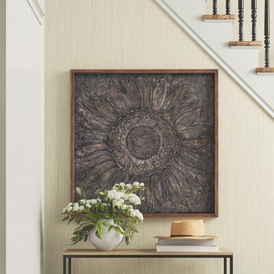 Realize your vision for a well-conceived room with this eye-catching wall decor. Crafted from iron with a distressed gray-brown finish, it depicts an embossed image of a sunflower. We love the highlights of metallic gold that make the petals pop. This piece measures 39” square, so it makes a statement in your space. It comes finished in a simple wood-tone frame that adds a rustic look, making this piece a good fit for a farmhouse or French country design aesthetic. Make sure to pick up the right Wall Decor For Modern Farmhouse, Dining Room Accent Wall Decor, Metal And Wood Wall Decor, Wall Decor Over Fireplace, Wood And Metal Wall Decor, Foyer Wall Decor, Metal Sunflower, Sunflower Wall Decor, Flowers Wall Decor