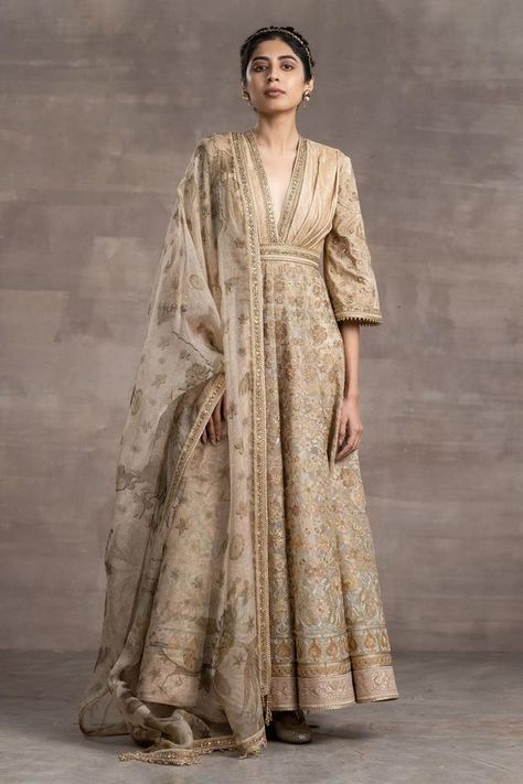 Beige anarkali with a pleated V-neckline., intricately embroidered in zari thread work all over and features a sheer-panelled back. Paired with a foil-jersey churidar and a printed tulle dupatta with gold zari borders. Component: 3 Pattern: Embroidered, Printed Type Of Work: Floral Pattern Neckline: V-Neck Sleeve Type: Bell Sleeves Fabric: Jersey, Foil Jersey, Tulle Color: Beige Other Details:  Pleated yoke Tassel hem dupatta Back cut-out with sheer panels Occasion: Sangeet - Aza Fashions Tarun Tahiliani Anarkali, Pattern Jersey, Anarkali Designs, Anarkali Churidar, Nikkah Dress, Embroidered Anarkali, Tarun Tahiliani, Engagement Outfits, Churidar