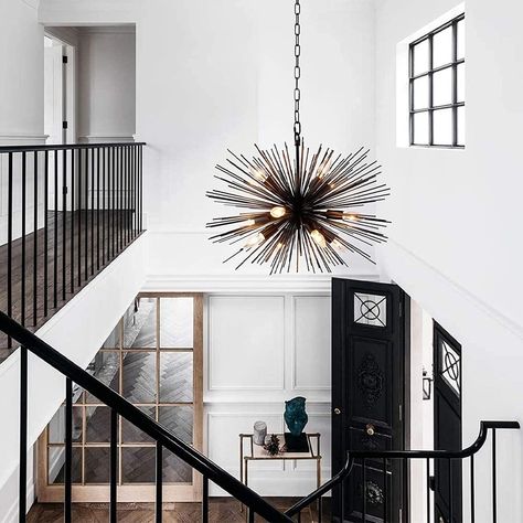 Light radiates from this chandelier. The chandelier is a striking departure from the ordinary. The lights are surrounded by black metal rods helping to set this light as the star of the room. With 12 dimmable lights it is as versatile as it is bold. Statement Chandelier Entryway, Black And Gold Light Fixture, Stairwell Chandelier, Entryway Light, Entry Chandelier, Front Foyer, Ideas Entryway, Starburst Chandelier, 12 Light Chandelier