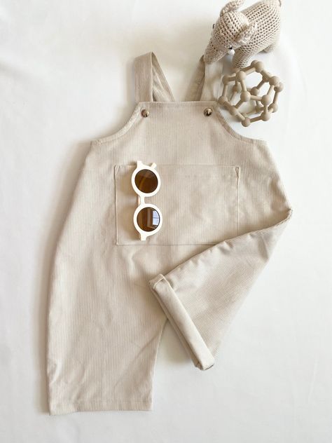 Step into comfort and style with our Kawa Handmade Oversized Corduroy Dungarees Romper, a delightful addition to your baby or toddler's wardrobe. Crafted with care, these wide-legged dungarees boast charming pocket detailing to the front and adjustable straps for a perfect fit. In a versatile Sand color, these dungarees add a touch of simplicity and sophistication to your little one's ensemble. Made from 100% Cotton, these dungarees prioritize comfort without compromising on style. The breathable fabric ensures a gentle feel against your child's skin, making it an ideal choice for all-day wear. The wide-legged design provides ample room for movement, allowing your little one to explore the world with ease. Pair these adorable dungarees with a chunky knit underneath for a cosy and stylish l Baby Romper Sewing Pattern, Corduroy Dungarees, Toddler Overalls, Baby Dungarees, Kids Overalls, Neutral Baby Clothes, Romper Outfit, Stunning Outfits, Corduroy Jacket