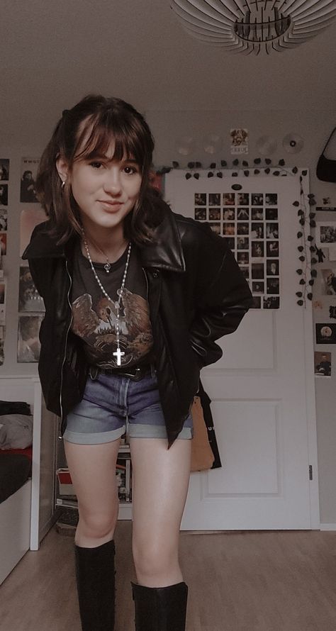 A girl standing in her room in shorts, a queen T-shirt, leather jacked, leather boots and a white cross-neckless Cool Rock Outfits, 50s Fashion Rock N Roll, 90 Rock Outfit, Rockstar Gf Outfits Summer, 80s Rock Women Outfits, Old Rock Concert Outfit, So Much For Stardust Outfit, Rock Band T Shirts Outfits Women, Simple Rock Concert Outfit