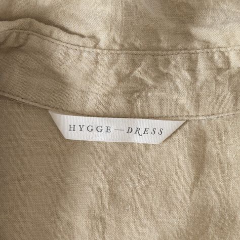 Logo that says Hygge Dress on a white label inside a shirt Couture, Linen Branding Logo, Dress Label Tag Design, Apparel Label Design, Neck Band Design, Clothing Label Inspiration, Clothing Brand Label Design, Fashion Tags Label Design, Cloth Label Design