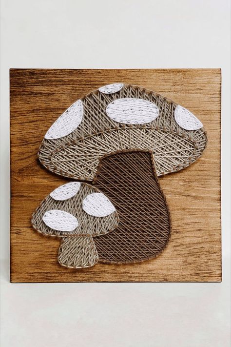 A large and small mushroom made in string art using dark and light brown tone string on a piece of stained wood. Mail And Thread Art, Nail And Yarn Art Designs, Wooden String Art, Highland Cow String Art, Mushroom String Art, Boho String Art, String Crafts Ideas, Nail String Art Patterns, Thread Art On Wood