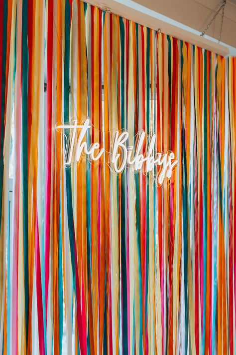 Backdrop For Neon Sign Wedding, Ribbon Wedding Backdrop, Colorful Ribbon Wedding, Country Fair Wedding Theme, Hens Party Photo Backdrop, Colourful Wedding Backdrop, Neon Photo Backdrop, Photo Back Drop Wall Ideas, Colorful Photo Backdrop