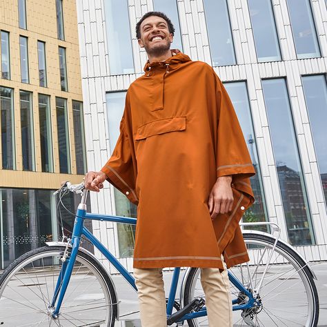 man standing with bike wearing  Imbris Rain Poncho Copper Urban Cycling, Windy Weather, Rain Poncho, Rainy Weather, Rain Wear, Mens Coats, Male Model, Water Repellent, Easy To Use