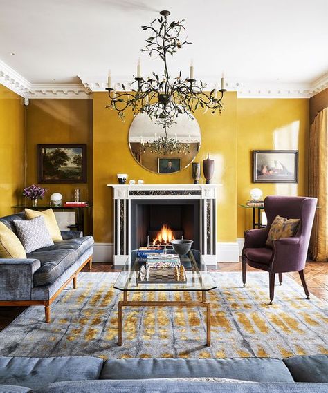 a quirky modern living room with mustard walls, a fireplace, a beautiful statement chandelier and elegant furniture Mustard Living Rooms, Yellow Walls Living Room, Houses In Poland, Mustard Yellow Walls, Yellow Decor Living Room, Mustard Walls, Victorian Living Room, Yellow Room, Yellow Living Room