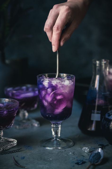 This color-changing, Harry Potter-inspired Polyjuice Potion cocktail is made with lemon, gin and butterfly pea powder for natural food coloring. The acid from the lemon juice turns the butterfly pea powder from a vibrant royal blue to a deep purple...bewitching to say the least! Harry Potter Inspired Drinks Non Alcoholic, Cocktails That Change Color, Purple Potion Drink, Polyjuice Potion Cocktail, Color Changing Cocktails, Harry Potter Mock Tails, Harry Potter Cocktails Recipes, Movie Foods, Butterfly Pea Powder