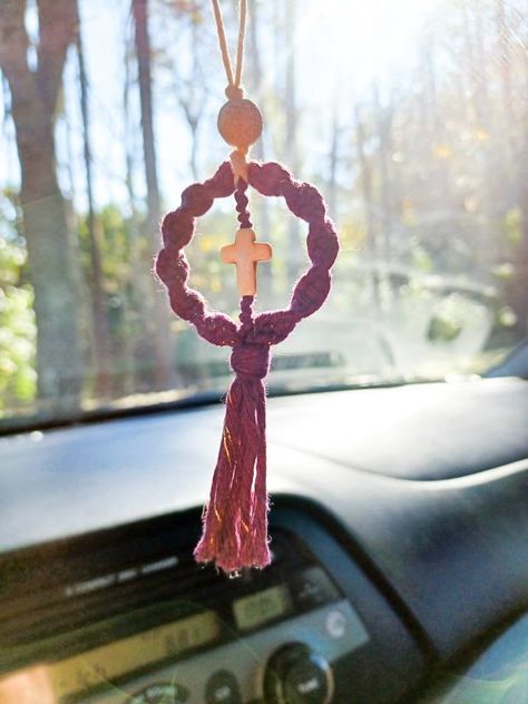 Rearview mirror car cross. Lava bead car hanger cross.  Bring a little joy to your family and friends with this unique gift. Great for Bible study group, family, friends, and coworkers.  Also, it can be used as a rear-view mirror car charm. The lava bead serves as a diffuser. Just add a few drops  of your favorite essential oil to the bead and enjoy.  * Ornament * Lava bead car diffuser  * Semiprecious cross bead * Made to order Colors: Peacock Blue Mustard Yellow Burnt Orange Gold Blueberry (Purple with white cross) * Gold Blueberry features a gold strand in the cord.  Also available without the gold strand, just choose the Blueberry option.  * Free shipping  on orders over $35 This cute Macrame diffuser is created with macrame  cord, lava bead, and semiprecious cross bead. If used as a c Cross Decorations, Car Hanging Accessories, Rearview Mirror Charm, Mirror Car Accessories, Diy Earrings Easy, Wire Knitting, Purple Car, Car Hangers, Rear View Mirror Decor