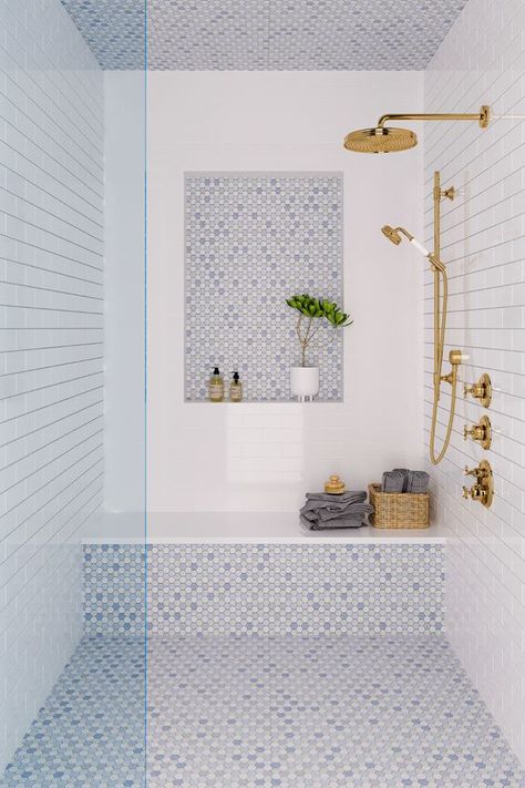 a coastal shower space done with white and blue tiles, a niche, a bench, some towels and gold fixtures Cappuccino Marble Bathroom, Master Bath Beach House, Bathroom With Teal Tile, Transom Window Shower Master Bath, Walk In Shower Ledge, Interior Shower Design, Master Bathrooms With Gold Fixtures, Blue White Shower Tile, Shower Enclosure Tiles
