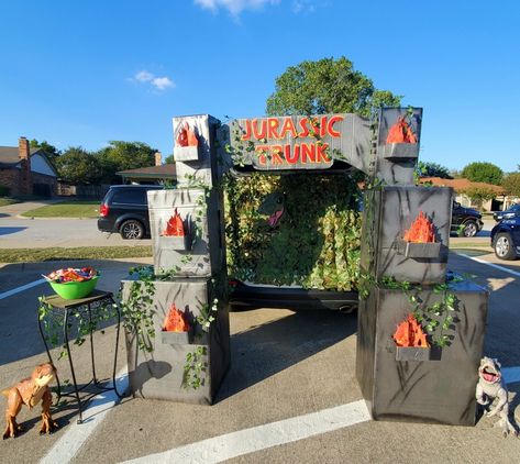 Trunk-or-Treat entry gates to Jurassic Park Jurassic Park Outdoor Decorations, Jurrasic Park Trunk Or Treat, Jurassic Park Trunk Or Treat Ideas, Fake Campfire, Camo Netting, Orange Led Lights, Faux Ivy, Jurassic Park Party, Jurrasic Park