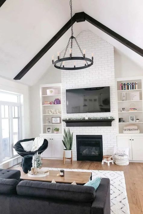 Emphasizing the height and spaciousness of a room, the contrast between the black-painted exposed beams and the pristine white ceilings in this living area is truly captivating. To achieve a modern farmhouse look, pair this design with a striking black candelabra chandelier. Black Ceiling Beams Living Room, Black And White Modern Farmhouse Living Room, Black And White Farmhouse Living Room, White Farmhouse Living Room, Black Beams, Beam Ideas, Ceiling Beams Living Room, Black And White Farmhouse, Black Candelabra