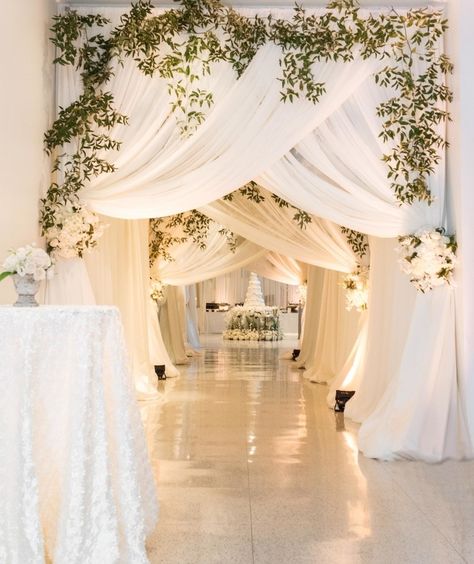 ###All-White Reception Draping  The Birmingham Museum of Art was transformed into an all-white wonderland with gallery passageways draped in sheer white chiffon and fresh greenery. The curtain tiebacks were fashioned from lush white florals; the pathway led straight to the couple’s stunning wedding cake. Shadi Decor, Walkway Decor, Wedding Reception Entrance, Wedding Draping, Draping Wedding, Reception Entrance, Wedding Entrance Decor, Cheap Wedding Flowers, Top Wedding Trends