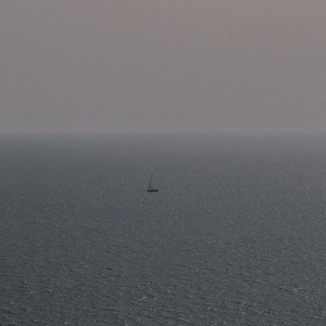 A sailboat drifts in solitude in a vast ocean shrouded in mist. Photo by Michele Pirelli #oceanlifestyle #sailboating #serene #petitefashion #petitestyleblogger #conciousfashion #sustainablefashionblogger #thepetitecartel Sailing, Petite Fashion, Vast Ocean, Mist, Fashion Blogger, Quick Saves