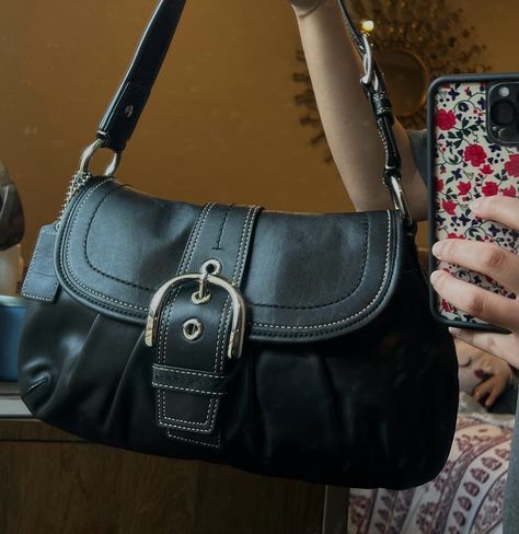 this is the black soho coach shoulder bag it has a buckle in the front and the sides. Black Satchel Bag Aesthetic, 90s Designer Bags, Coach Soho Shoulder Bag, Vintage Black Coach Bag, Buckle Shoulder Bag, Coach Black Shoulder Bag, Big Shoulder Bags Aesthetic, Vintage Coach Soho Bag, Black Everyday Bag