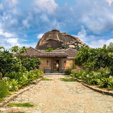 Andagere Architects designed the entrance to be intentionally humble, deferring to the statuesque Kengal Village hill that towers above. Village Entrance, Granite Stairs, Polished Cement, Carpentry Workshop, Village Home, Rammed Earth Wall, Indian Village, Natural Swimming Pool, Rammed Earth