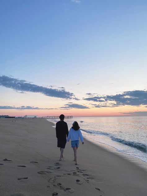 A couple is walking down the shore during sunrise. There are cotton candy skies + a boardwalk in the background Picture Sweet Couple, Beach Dating Aesthetic, Tumblr, Relationship Beach Aesthetic, Morning Date Aesthetic, Things To Do In Beach, Sunrise Date Ideas, Beach Date Pictures, Beach Dates Couple