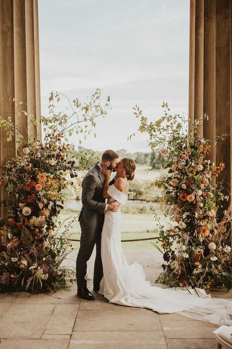 Bride and groom kiss inbetween pillars with orange, peach and white flower column altar decorations Flower Columns, Wedding Alter Flowers, Wedding Altar Decorations, Altar Flowers Wedding, Civil Wedding Ceremony, Diy Wedding Centerpiece, Wedding Columns, Alter Flowers, Wedding Pillars