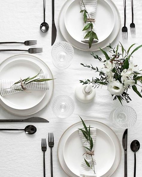 Classic meets modern table setting for thanksgiving or Christmas. Clean and crisp white linens mixed with two stacked white plates using a charger, pewter cutlery and simple greens tied up in the cloth napkins. Minimal Table Setting, Modern Tablescape, Minimal Table, Modern Table Setting, Tafel Decor, White Dinner, Table Set Up, Pretty Tables, Christmas Table Settings