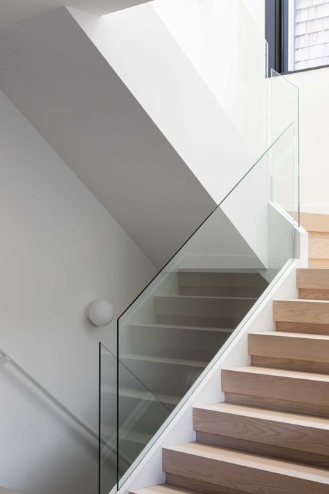 Wood stairs with a glass railing connect the various levels of this modern home. Stained Oak Cabinets, White Oak Staircase, Glass Stairs Design, Glass Staircase Railing, Glass Railing Stairs, Oak Staircase, White Staircase, Staircase Design Modern, Glass Railings