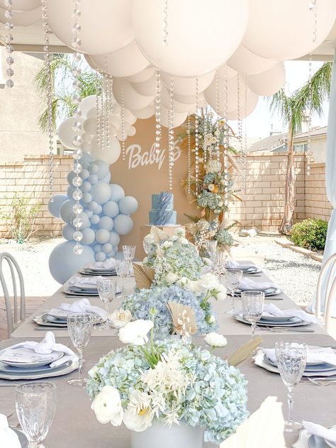 Event Du Jour flawlessly executed this blue and white baby shower. Pearl details cascaded from the balloon arrangement suspended above the table topped with arrangements of blue hydrangeas and white peonies. Unique charger plates and textured glassware furthered the picture-perfect tablescape. April Boy Baby Shower Ideas, Spring Boy Baby Shower Themes, Neutral Blue Baby Shower Ideas, Classy Boy Baby Shower Ideas, Classy Baby Boy Shower Ideas, Outdoor Babyshowers, Bris Decor, Pastel Blue Baby Shower Ideas, Elegant Baby Boy Shower Ideas