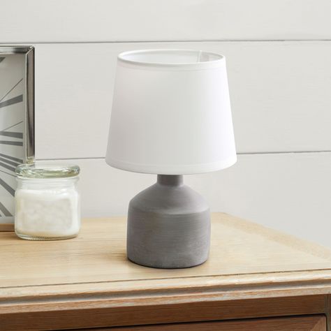 "Buy the Simple Designs Mini Bocksbeutal Ceramic Table Lamp at Michaels. com. The painted cement base and white empire shade maintains a neutral feel to each of the available base color options. Light up your space with this tastefully crafted table lamp. The painted cement base and white empire shade maintains a neutral feel to each of the available base color options. This small, yet practical table lamp fits perfectly atop your night stand, office desk, or living room console. Details: Availa Battery Operated Lamps, Concrete Table Lamp, Rustic Table Lamps, Empire Shade, Living Room Console, Mini Table Lamps, Grey Table Lamps, Mini Lamp, Concrete Table