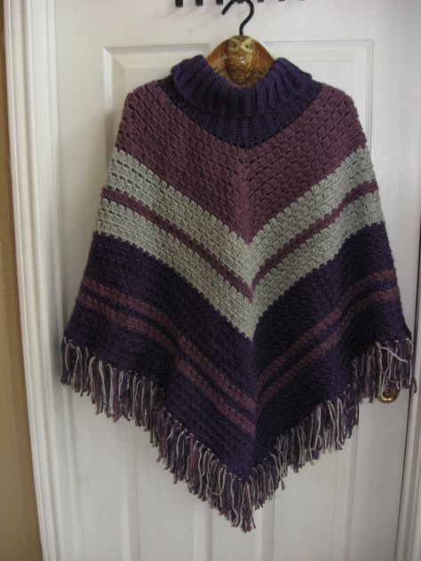 "This Sporty Cowl neck poncho is made with two shades of purple and gray. The fringe are 4 1/2 \" long.  This poncho would be nice for wearing to football games or a night out on the town.  Instead of wearing a coat in the car in the winter months, this poncho is an excellent substitute to keep you warm and your arms free.   Fits XL-4X.  Machine wash and dry inside a pillow case to keep the fringe intact." Ponchos, Poncho Ideas, Crochet Shrugs, Cowl Neck Poncho, Turtleneck Poncho, Ladies Poncho, Crochet Shrug, Knitted Poncho, Be Nice