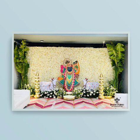 We wanted to let you know that we recently designed a beautiful flower pasting backdrop of Shree Nath ji. We used high-quality Ramban and Rajnigandha flowers for the arrangements, and for the spiritual backdrop, we used white Desi flowers with a brass prop. The overall effect was stunning and created a serene atmosphere. We would love to discuss more with you about our flower arrangement services and how we can help create a beautiful and meaningful atmosphere for your next event. Mayra Decoration, Pichwai Designs, Desi Flowers, Krishna Background, Leaf Decor Wedding, Ganpati Decoration Theme, Puja Ghar, Indoor Wedding Decorations, Simple Stage Decorations