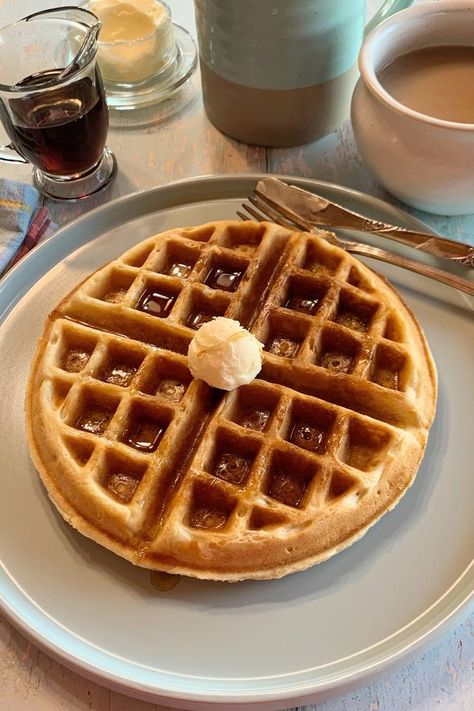 A Belgian waffle with butter and syrup on top.