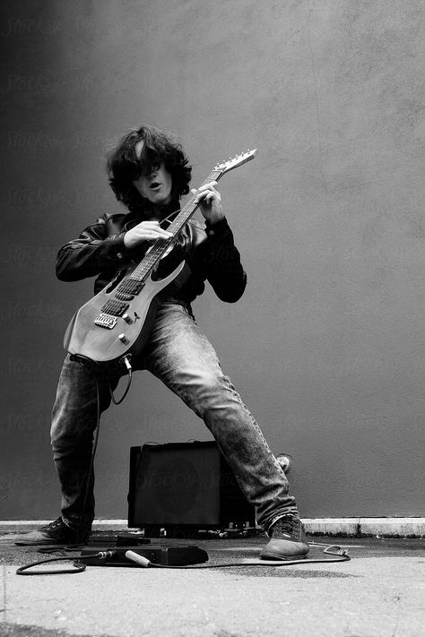 Black and white portrait of stylish rock musician playing electric guitar in the street against of wall Rockstar Playing Guitar, Poses With Electric Guitar, Person Playing Electric Guitar Reference, Guitar Playing Poses, Guitarist On Stage, Portraits With Guitar, Guitar Poses For Men, Street Musician Photography, Rock Star Pose Reference