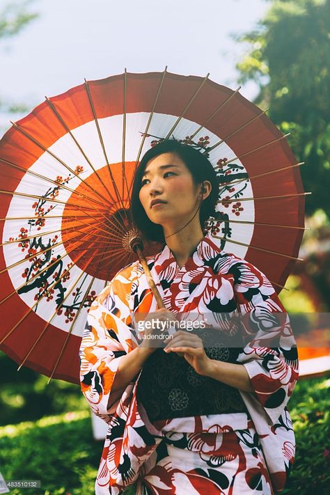 Beautiful japanese woman stand in the park. She wears kimono, obi and hold oil paper umbrella.The kimono is very colorful and elegant. She seems very pensive. Standing With Umbrella Pose, Geishas, Woman Holding Umbrella Reference, Japanese Paper Umbrella, Holding An Umbrella Reference, Holding Parasol Pose, Holding Umbrella Pose Reference, Holding Parasol Reference, Elegant Standing Poses Reference Drawing