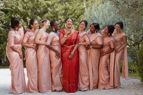 Bridal party with bride in a red lehenga and pink bridesmaids dresses Red Saree Bride With Bridesmaid, Indian Bridesmaids Saree Outfits, Sari Bridesmaid Dress, Saree Bridesmaid Wedding, Indian Bride With Bridesmaids, Pink Bridesmaid Saree, Bridesmaid In Saree, Tamil Wedding Bridesmaid, Tamil Bridesmaid