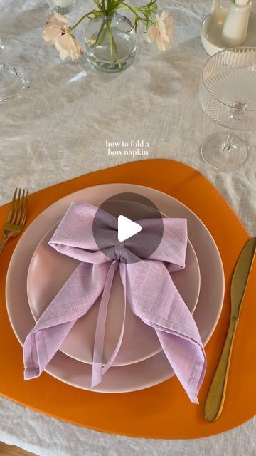 Ashley Tassano on Instagram: "I decided to add this bow napkin last minute, and I’m so happy I did. Not only was it simple, but everyone loved it! You could also make these with a napkin ring or a clear elastic instead of the ribbon.   Tip: Save the ribbon to use again or add it to glassware for your next event. ✨  #coquette #bows #napkinfolding #tablescapes #tablescapestyling #tablescapetuesday #discover" Napkin Fold With Ribbon, Napkins With Ribbon Place Settings, Tying Napkins With Ribbon, How To Fold A Bow Tie Napkin, Napkin Bow On Tea Cup, How To Fold A Napkin Into A Bow, Napkin Ring Fold, Bow Napkin Ring, Napkins Tied With Ribbon