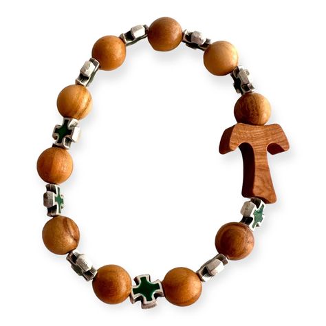 This stretch bracelet features ten beads, each meticulously handcrafted from wood, providing a natural and rustic feel. The centerpiece of this unique piece is the Tau Cross, a symbol of faith and protection. Interspersed among the wooden beads are green Celtic crosses, adding a touch of color and further spiritual symbolism to the bracelet. This bracelet is not only a statement of faith but also a piece of art that showcases the skill of the craftsmen who made it. It's a perfect accessory for those who appreciate the beauty of religious symbols and the craftsmanship of handmade in Italy jewelry. Celtic Crosses, Tau Cross, Italy Jewelry, Wooden Bracelet, Religious Symbols, Celtic Cross, Catholic Gifts, Rustic Feel, Stretch Bracelet