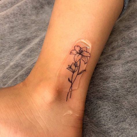 Creative Ankle Tattoos, Where To Put A Flower Tattoo, Lily Flower Tattoos Ankle, Fine Line Flower Tattoo Matching, Lily Flower Line Tattoo, May Lilly Flower Tattoo, May Lilly Tattoo, Fine Ankle Tattoo, Lily Flower Ankle Tattoo