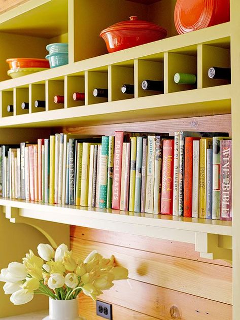 Oh, what to do with all those cookbooks? This bright bookshelf/storage wall solves that problem with style. Simple cubbies above the books store single bottles of wine, and colorful baking and serving dishes are displayed on the shelves above. Cookbook Display, Cookbook Storage, Kitchen Bookshelf, Decor Above Cabinets, Cookbook Shelf, Kitchen Furniture Storage, Inset Cabinets, Above Kitchen Cabinets, Above Cabinets