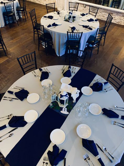 Simple yet elegant wedding reception decor. Navy napkins with rhinestone napkin holder. Centerpieces are white lanterns with navy and silver accents. Central Florida wedding planners. Navy Blue Silver White Party Decorations, Navy Silver White Party Decorations, Navy Silver And White Wedding, Navy Silver White Wedding, Teal And White Wedding Reception, Napkin Decoration Ideas Wedding, Navy And Silver Decorations, Navy Blue Silver And White Party Decor, Navy And Silver Wedding Centerpieces