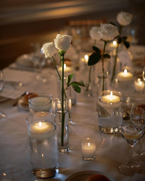 Simple single white roses and candles wedding table decor Simple Rose Table Centerpieces, Simple Romantic Table Decor, Single Rose In Vase Wedding, White Roses In Bud Vases Wedding, White Rose Simple Centerpiece, Simple Wedding Candle Centerpieces, Simple Roses Centerpieces, Single Rose Table Centerpiece, Simple Floral Table Decorations