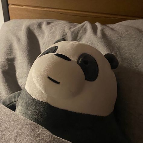 A stuffed animal of panda from we bare bears tucked into bed