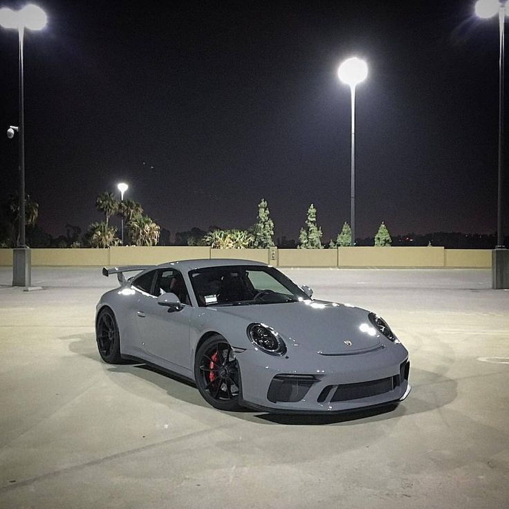 a white sports car parked in an empty parking lot at night with street lights on