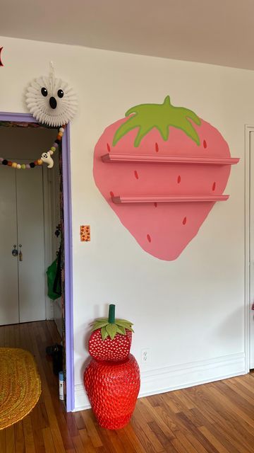 there is a strawberry on the wall next to a red vase