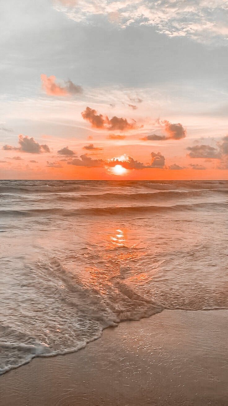 the sun is setting over the ocean with waves coming in to shore and some clouds