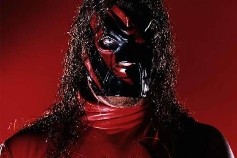 a man with long black hair wearing a red mask and leather outfit, standing in front of a red background