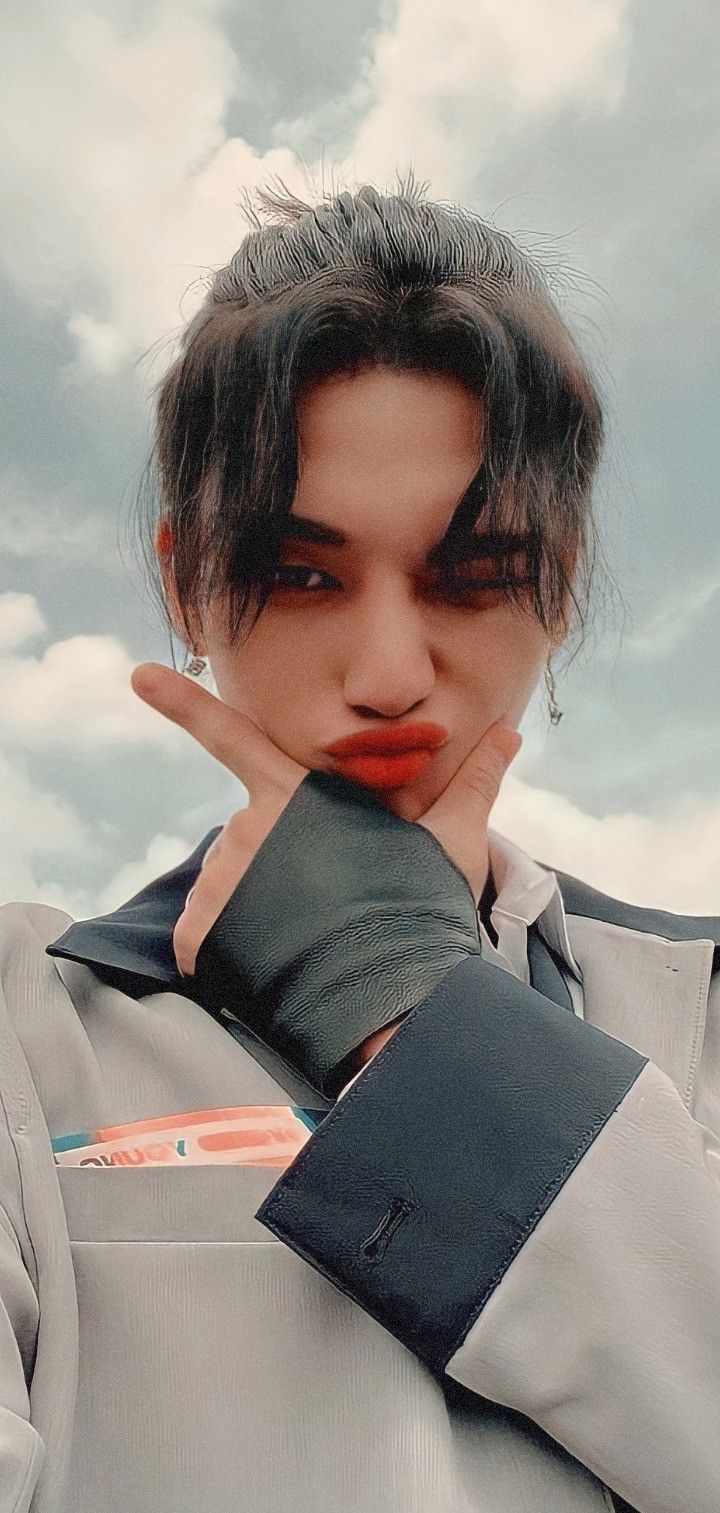 a woman with short hair and red lipstick holding her hand up to her face in front of the camera