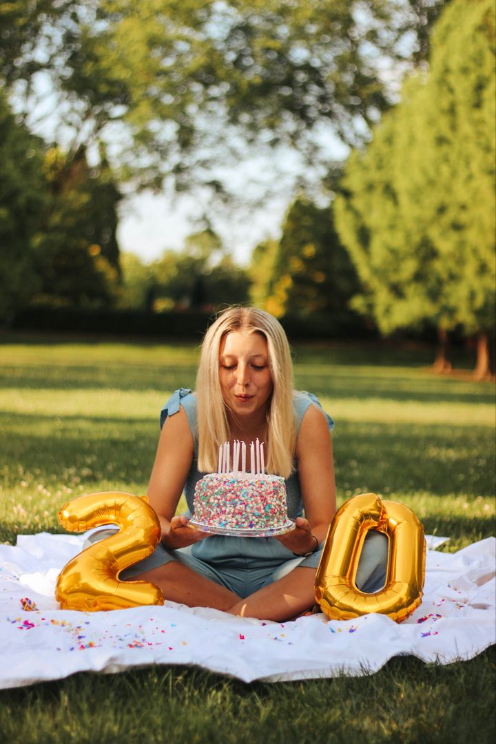 a woman sitting in the grass with balloons that say 20