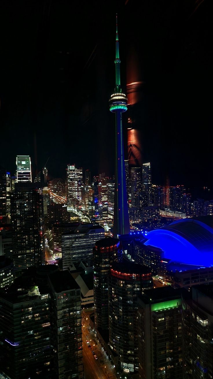 an aerial view of the city at night with lights on and buildings lit up in blue
