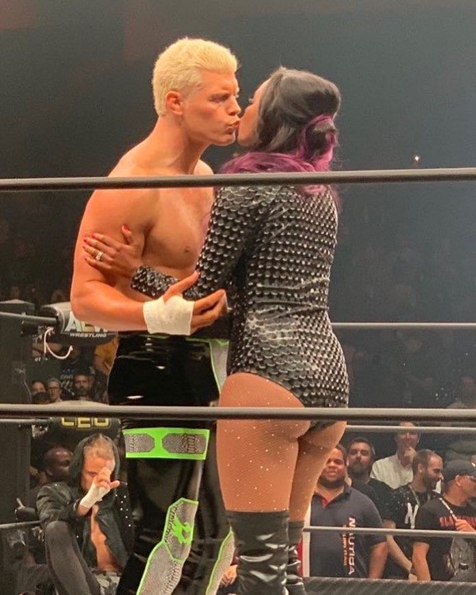 two people standing next to each other in a wrestling ring, one kissing the other