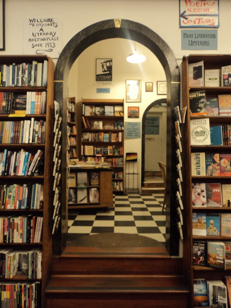 an arched doorway leads to a library filled with books and magazines on the shelves, along with a checkered black and white floor