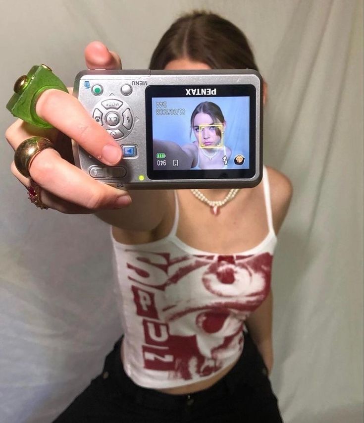 a woman holding up a cell phone to take a selfie with her face on the screen